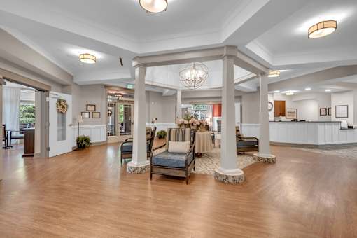 A spacious lobby with a wooden floor and a large chandelier.