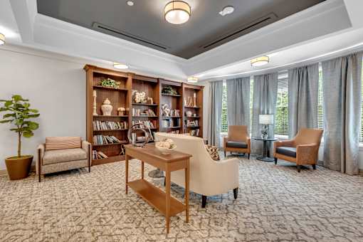 A living room with a carpeted floor and a bookshelf filled with books.
