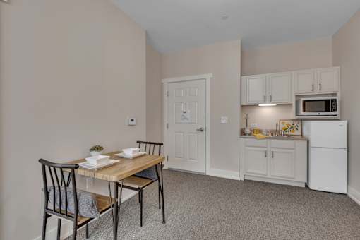 A kitchen area with a table and chairs.
