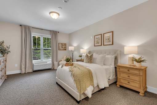 A bedroom with a large bed, a window with curtains, and a nightstand with a plant on it.