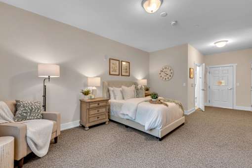 A bedroom with a bed, nightstand, and chair.