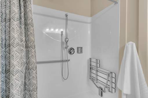 A shower with a curtain and a white towel hanging on the side.