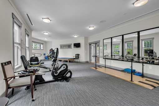 A spacious gym with a variety of equipment including a treadmill, exercise bike, and a bench.