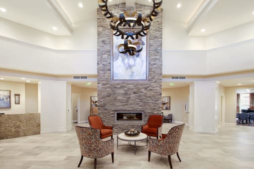 A living room with a stone fireplace and a large painting above it at White Springs Senior Living, Warrenton
