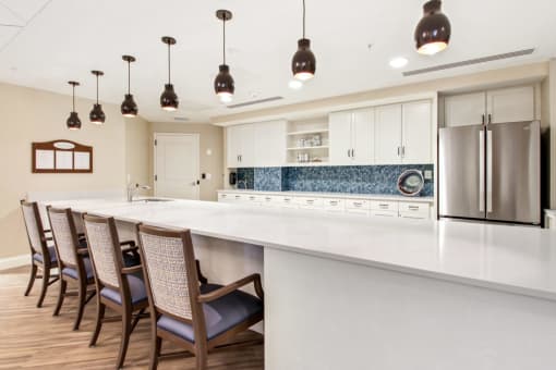 A kitchen with a long white counter and chairs at White Springs Senior Living, Virginia