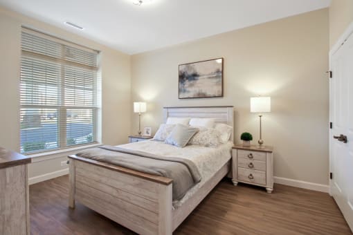 A bedroom with a large bed, nightstand, and a painting on the wall at White Springs Senior Living, Warrenton, VA 20186