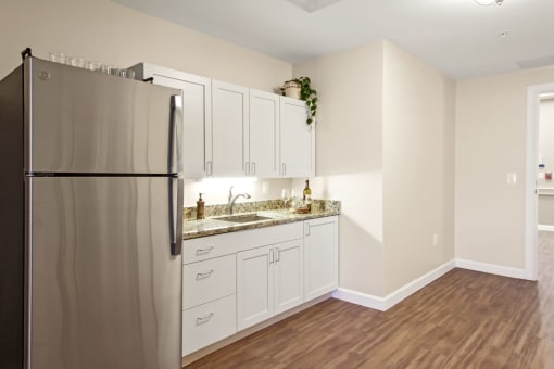 A kitchen with a refrigerator, sink, and cabinets at White Springs Senior Living, Warrenton, VA