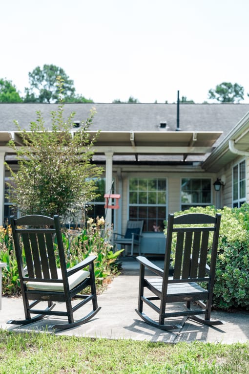 Two rocking chairs on a patio in front of a house Spring Arbor of Apex