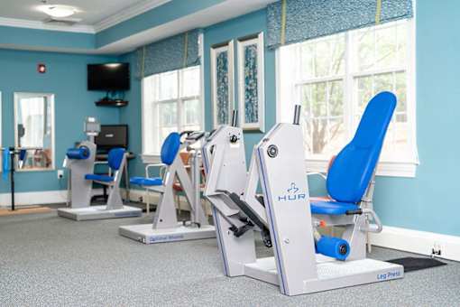 Gym with cardio machines and chairs in a room with windows at Spring Arbor of Rocky Mount