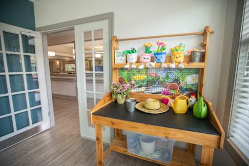 A wooden shelf with various potted plants and gardening tools.at Spring Arbor of Wilson, Wilson North Carolina