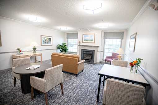 A living room with a fireplace and a dining table.at Spring Arbor of Wilson, North Carolina, 27893-2873