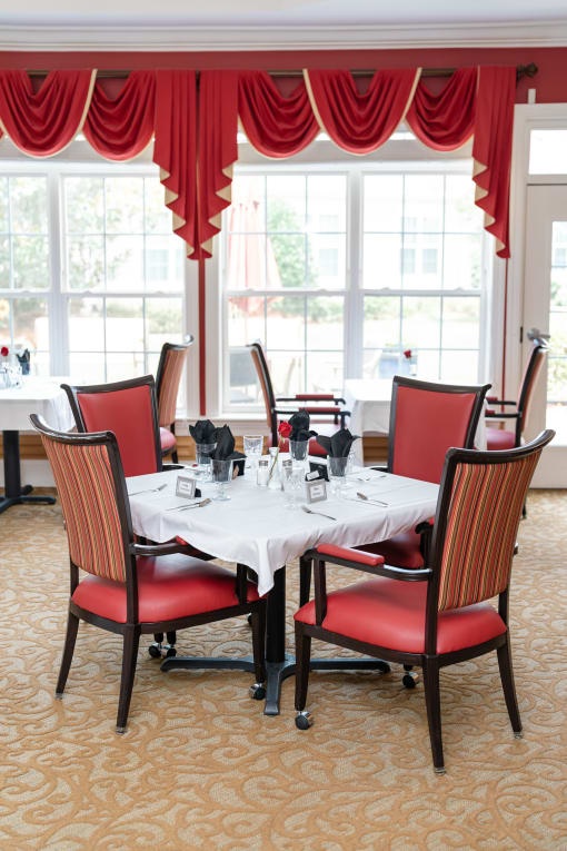 Dining room table with red chairs and windows Spring Arbor of Cary, Cary