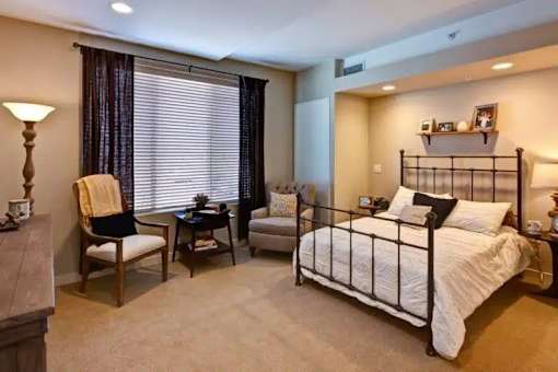 A bedroom with a bed, chair, and table at The Piper, Kansas City, KS.