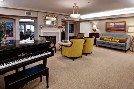 A living room with a piano, sofa, and chairs at The Piper, Kansas City, KS.