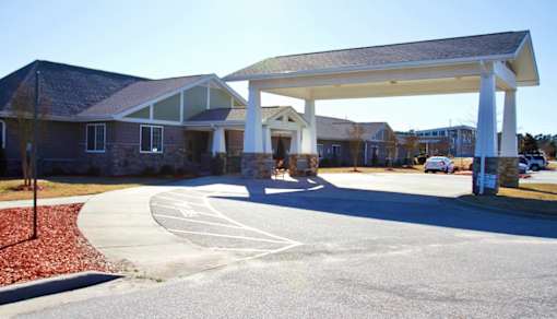 A white covered walkway leads to a building with a brick facade.