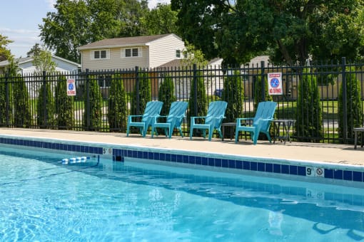 Outdoor pool with turquoise lounge chairs and black fence at Fox Run Apartments, St. Charles, IL