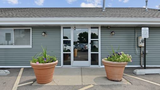Building entrance with terracotta planters and glass doors at Fox Run Apartments, St. Charles