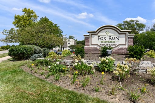 Monument sign with brick base and seasonal flowers at Fox Run Apartments, St. Charles, IL