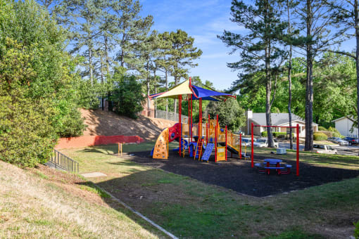 a playground in a park with trees and a hill in the background