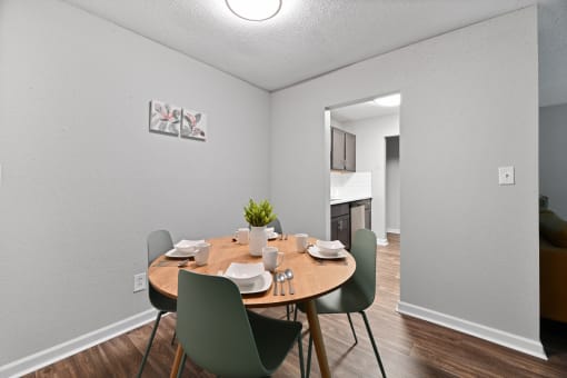 a dining room with a table and chairs and a kitchen in the background