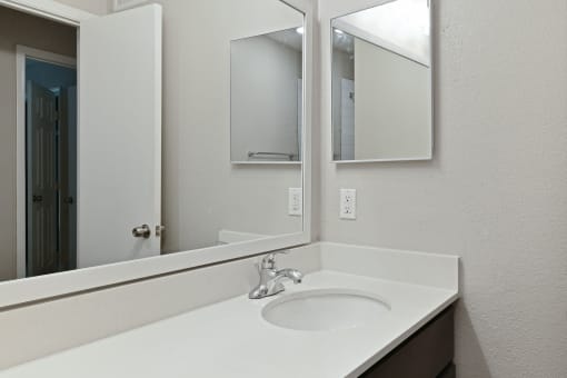 a bathroom with a sink and two mirrors