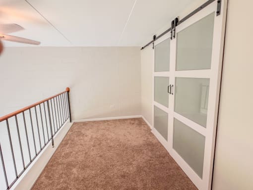 Carpeted loft space with barn door closet at Fox Run Apartments, St. Charles