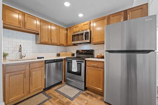 Corner kitchen with wood cabinetry and stainless appliances at Fox Run Apartments, St. Charles, IL 60174