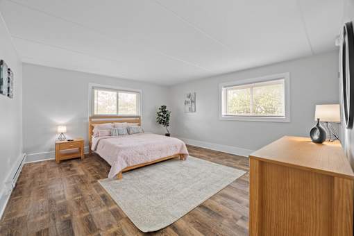 Spacious bedroom with wood style flooring and area rug at Fox Run Apartments, St. Charles, IL