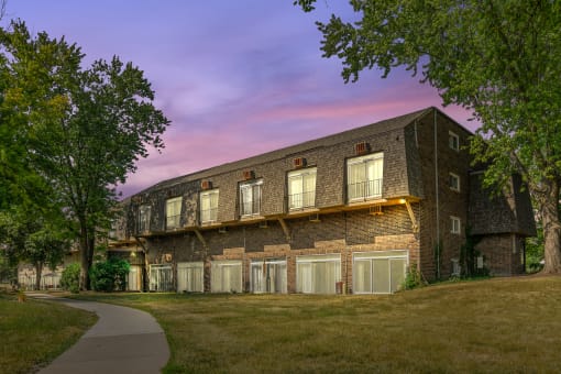 Brick apartment building exterior at twilight with garages at Fox Run Apartments, Illinois, 60174
