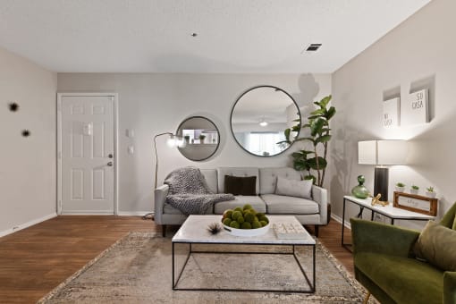 a living room with a couch coffee table and two mirrors