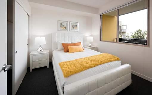A bedroom with a white bed and a yellow pillow.