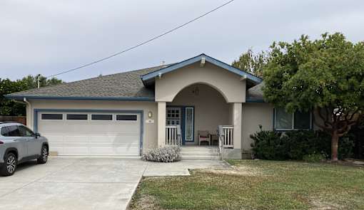 A house with a blue garage door and a grey car parked in front.