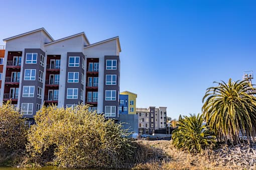 A modern apartment building with a yellow accent building in the background.