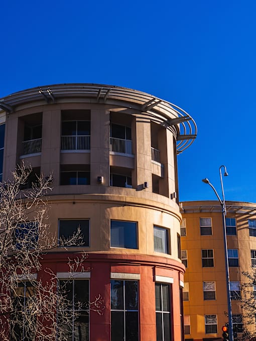 A curved building with a balcony and a street light in front of it.