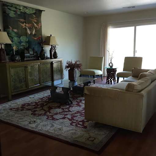 A living room with a couch, chairs, and a rug.