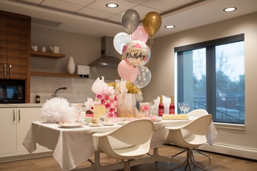 a birthday party with a white table and pink and gold balloons
