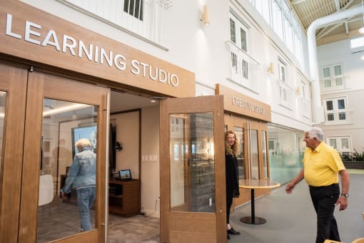 a man and a woman walk into a building with a sign that reads learning studio