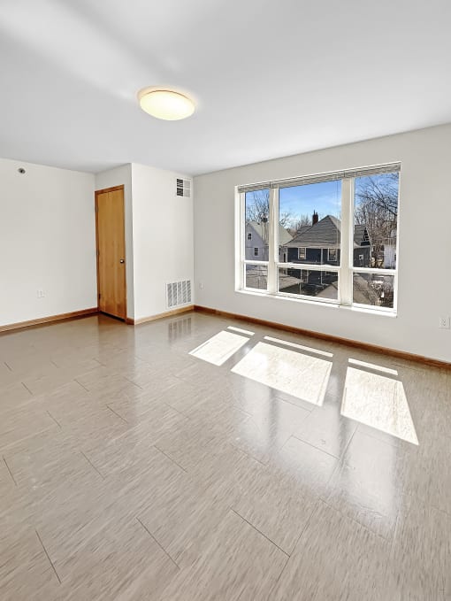 an empty living room with a large window and wooden floors