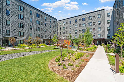 the courtyard of an apartment building with grass and trees
