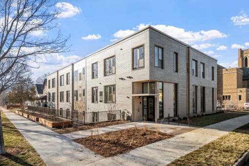 the exterior of a three story apartment building with a sidewalk