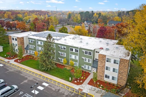 an aerial view of a building with a parking lot and trees
