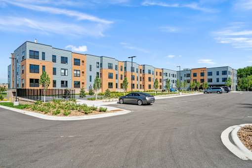 A modern apartment complex with a parking lot in front.