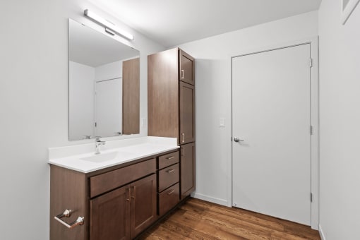 A bathroom with a sink, mirror, and wooden cabinets.