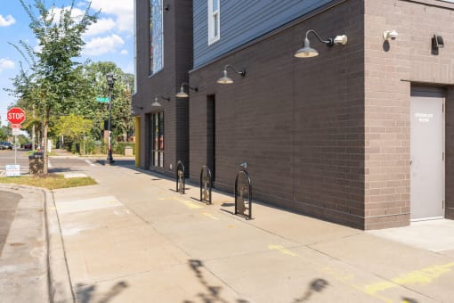 the side of a building with a sidewalk and bike racks