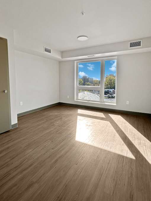 an empty living room with wood flooring and a window