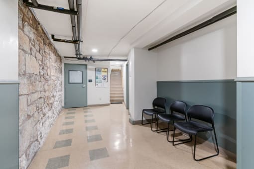 a hallway with chairs and a brick wall and a door