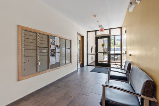 the lobby of a building with chairs and a bulletin board on the wall