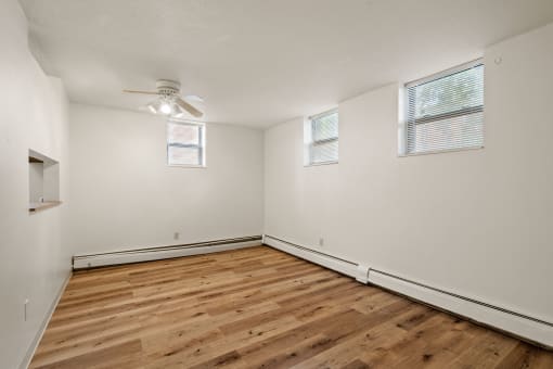 the spacious living room with wood flooring and a ceiling fan