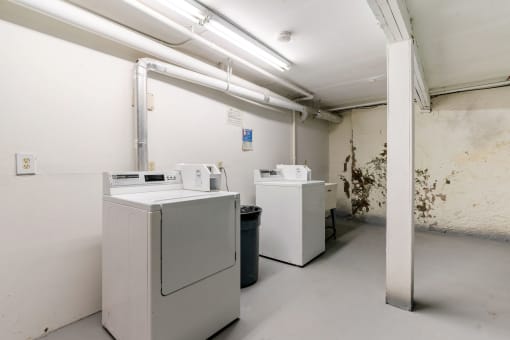 three washing machines in a white room with a dirty wall