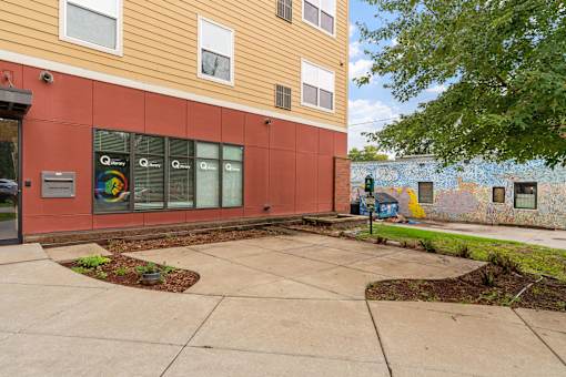 a sidewalk in front of a building with a mural on the side